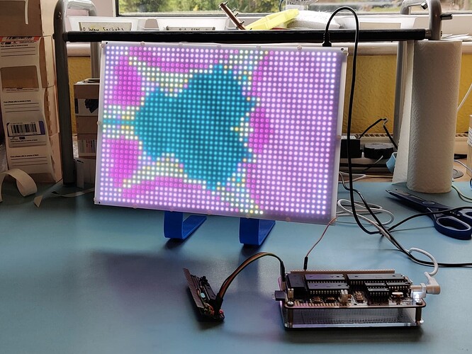 Spikey not-quite-Mandelbrot fractal image on bright colourful LED display screen with homebrew electronics on the desk next to it.